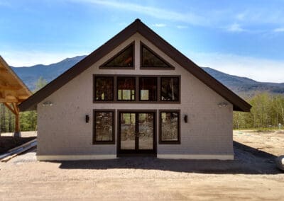 Exterior of Modern Barn with grey shingles, timber frame solar panel, and mountains in the background.