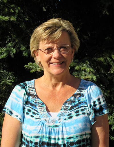 Smiling woman in front of pines trees