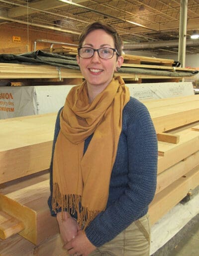 Woman standing in front of a stack of timbers.