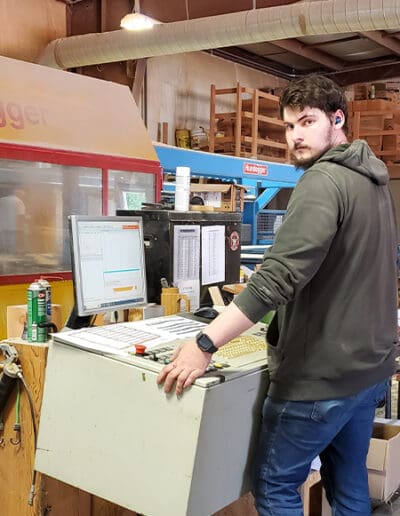 Man standing at computer and operating Hundegger machine.