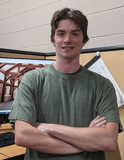 Man standing at desk with timber frame rendering on computer