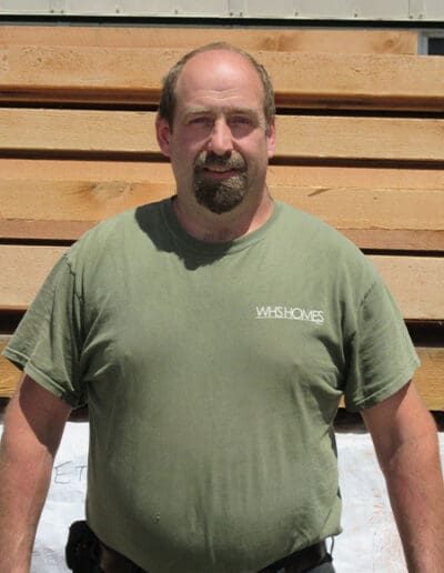 Man standing in front of stack of timbers.