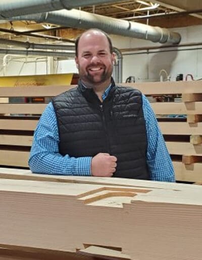 Man leaning against timbers with the Hundegger machine in the background.