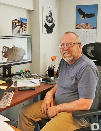 Man sitting at his desk with computer showing timber frame design