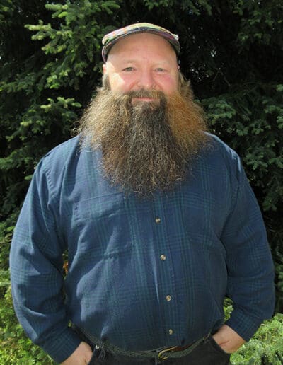 Man standing in front of pine trees