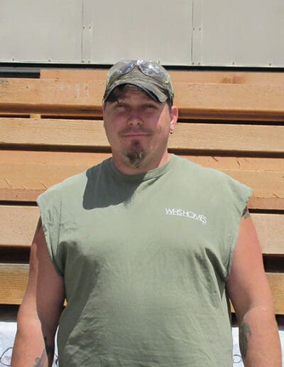 Man standing in front of a stack of timbers