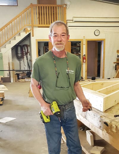 Man standing in River Road workshop and holding a drill.