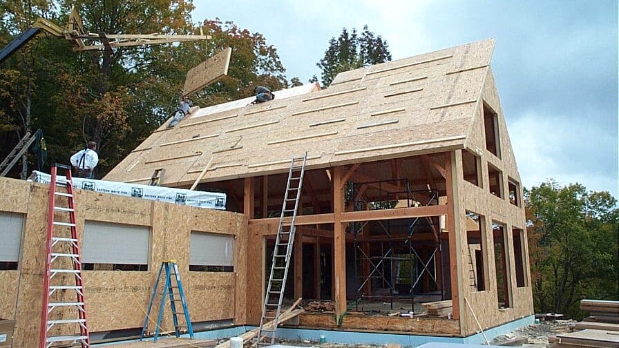 View of frame raising with two workers and surrounded by snow.