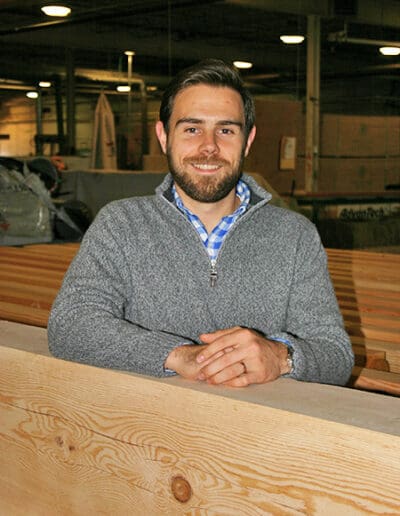 Man standing in workshop surrounded by timbers.